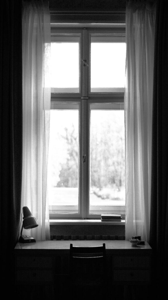 black and white photo of window with table and chair